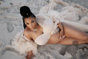 Maternity beach photoshoot featuring flowy champagne-colored dress against sandy backdrop.