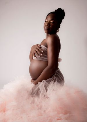 Elegant maternity portrait with expectant mother in pink tulle skirt.