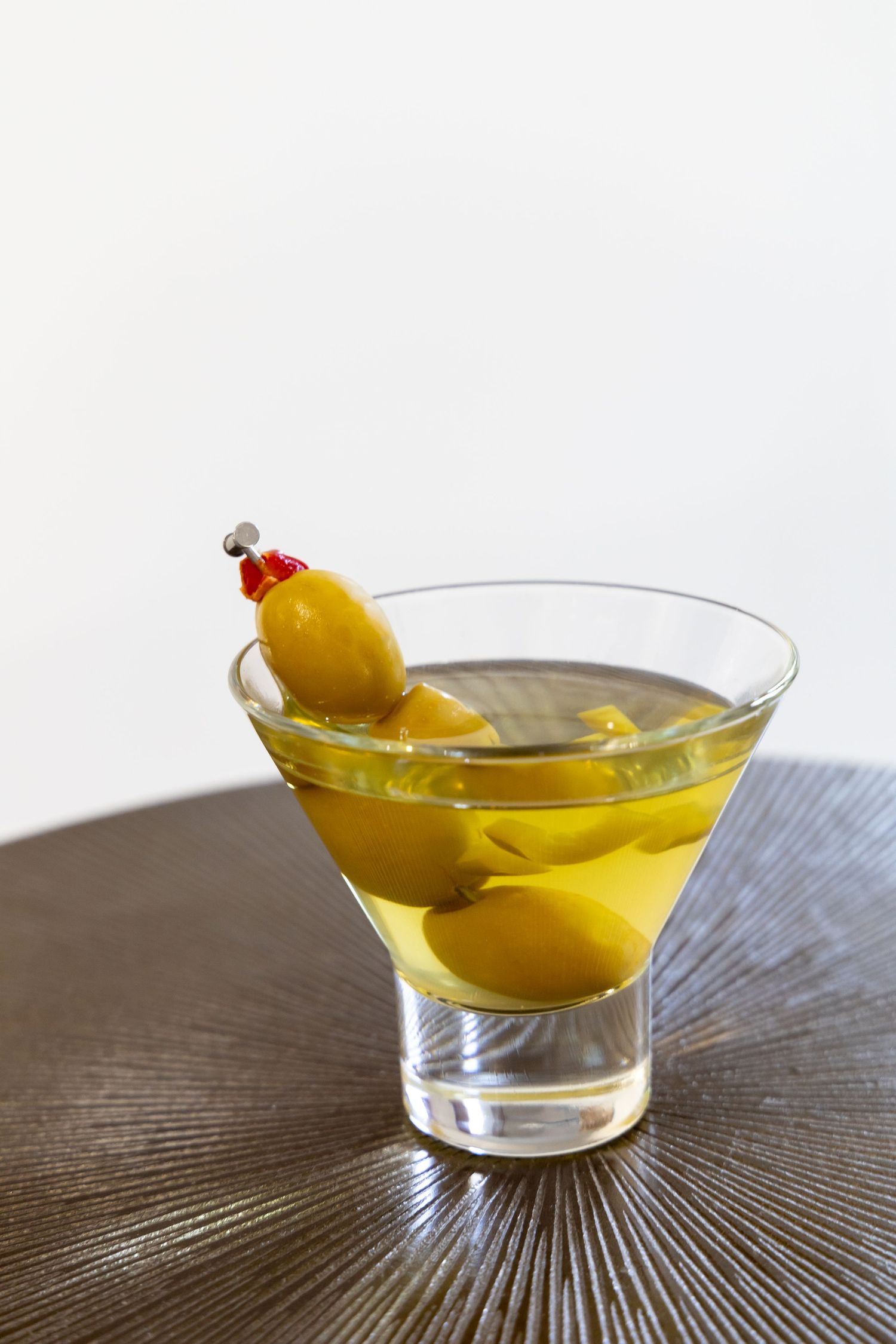 Classic martini cocktail garnished with yellow olives in stemmed glass.