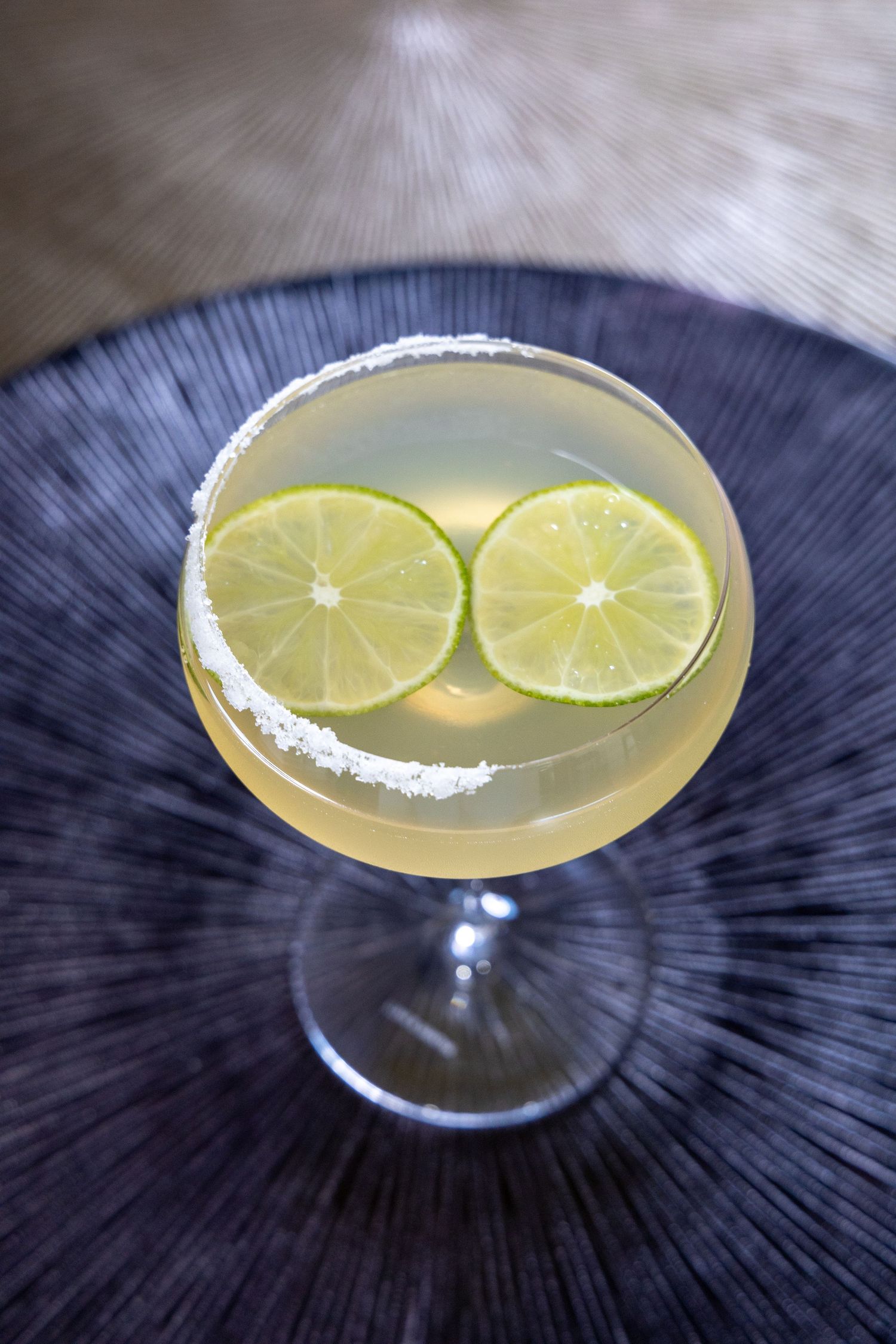 Citrus cocktail garnished with lime wheels and sugar rim in classic martini glass.