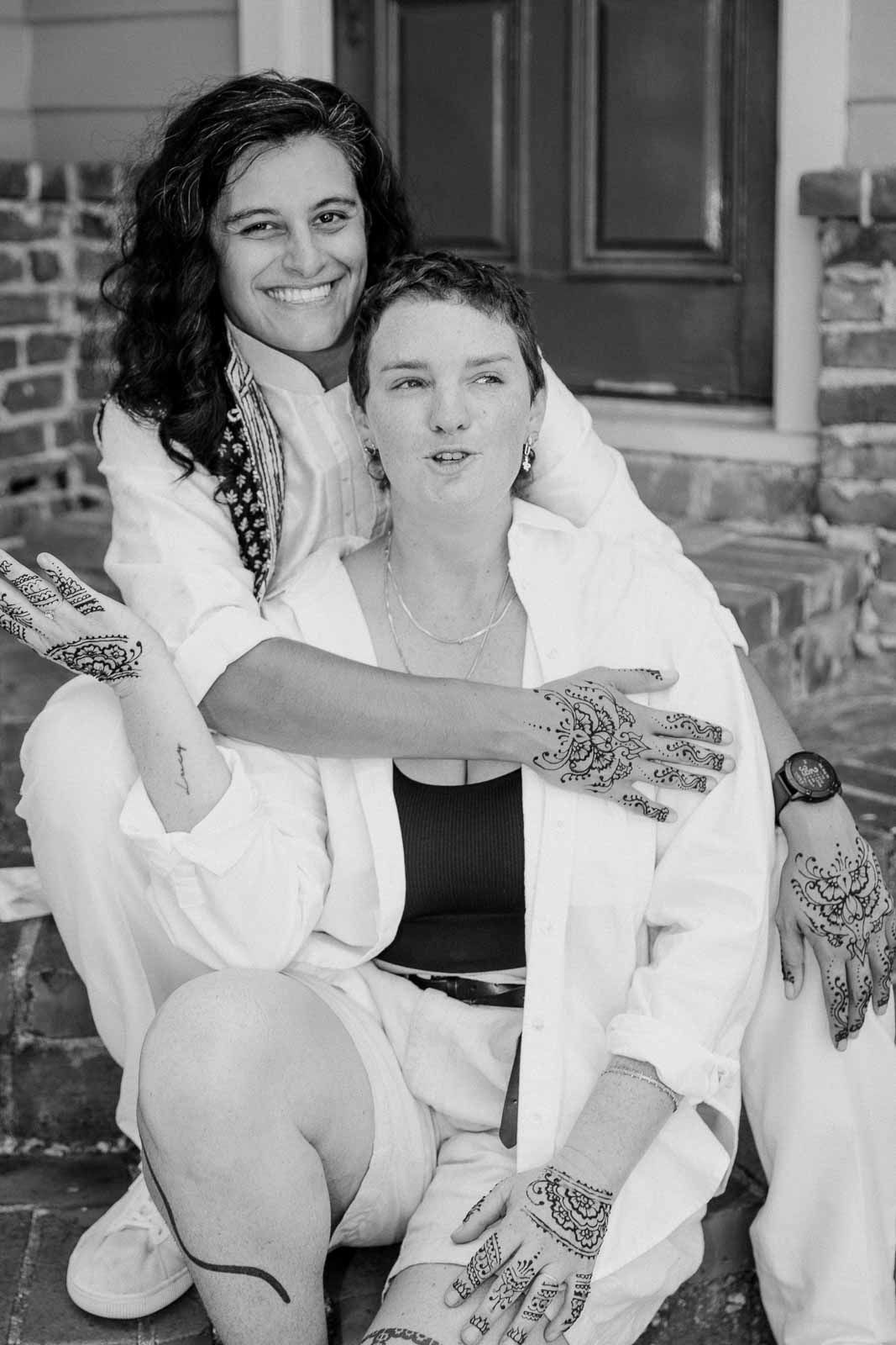 Black and white portrait showing tattoos and henna designs on hands.