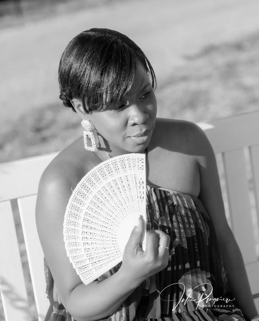 A monochrome portrait with decorative hand fan in natural lighting.
