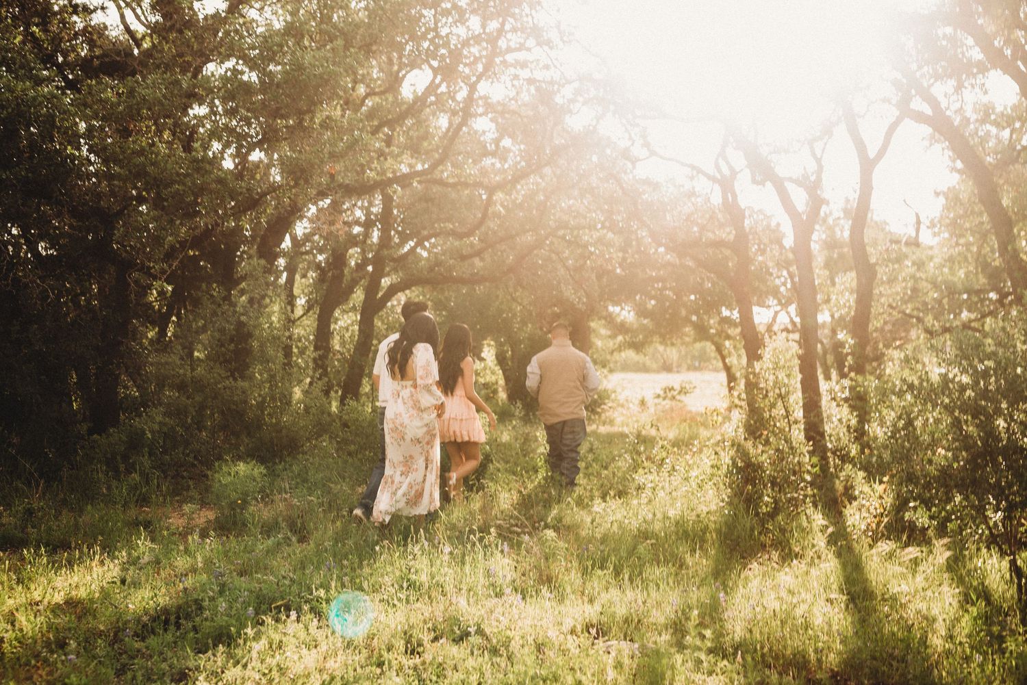 Couple walking through sun-dappled field during golden hour photo session.