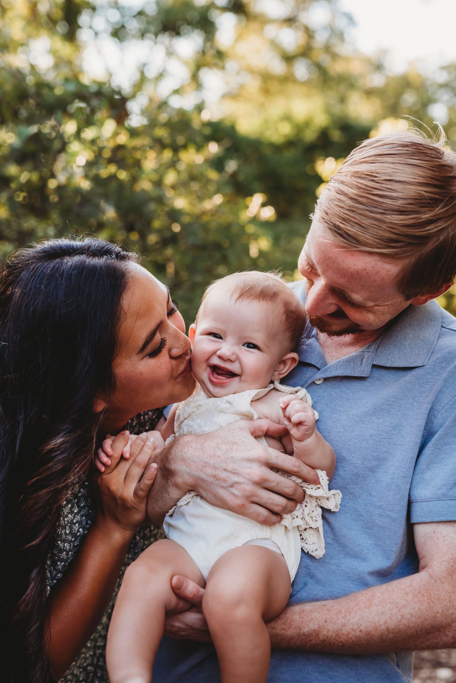 Joyful intimate family moment captured with laughing baby and loving parents.