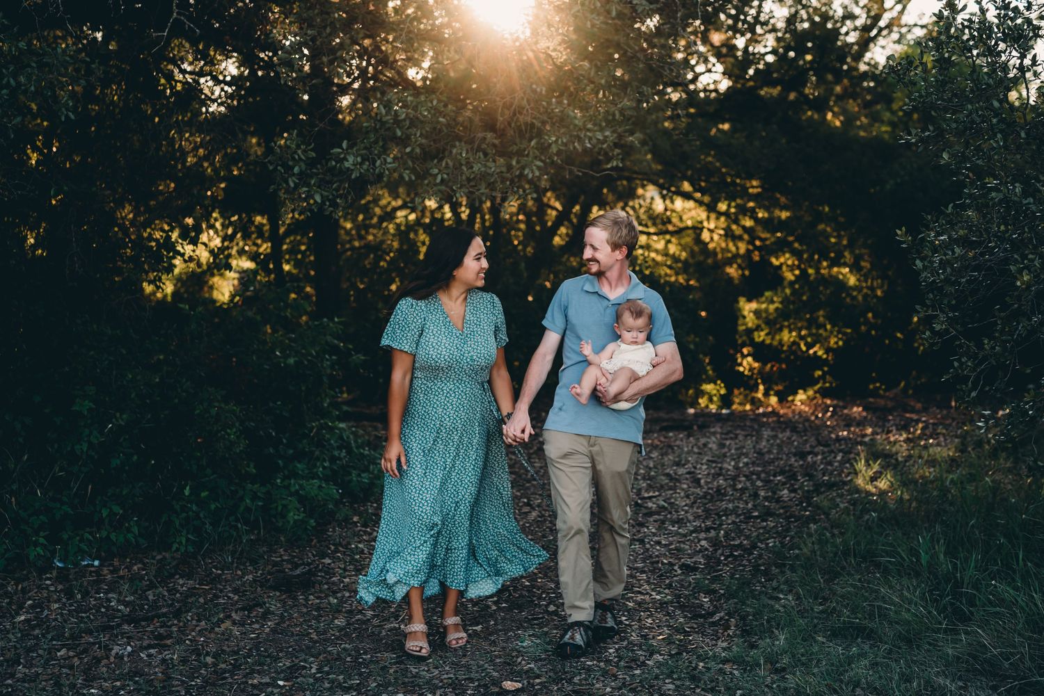Couple walking hand in hand on nature trail during sunset wearing casual clothes.