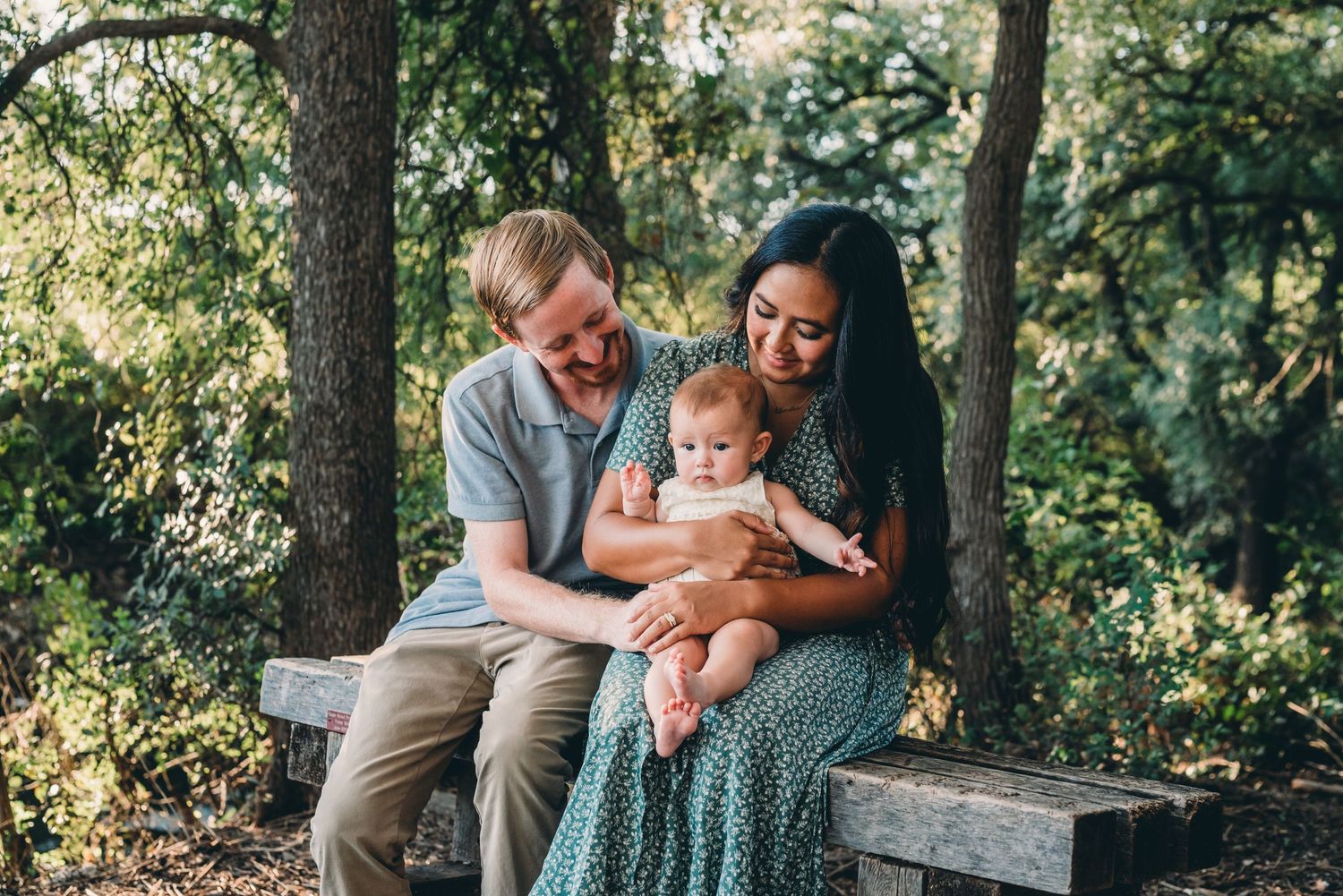 Happy family enjoying outdoor photo session on rustic bench.