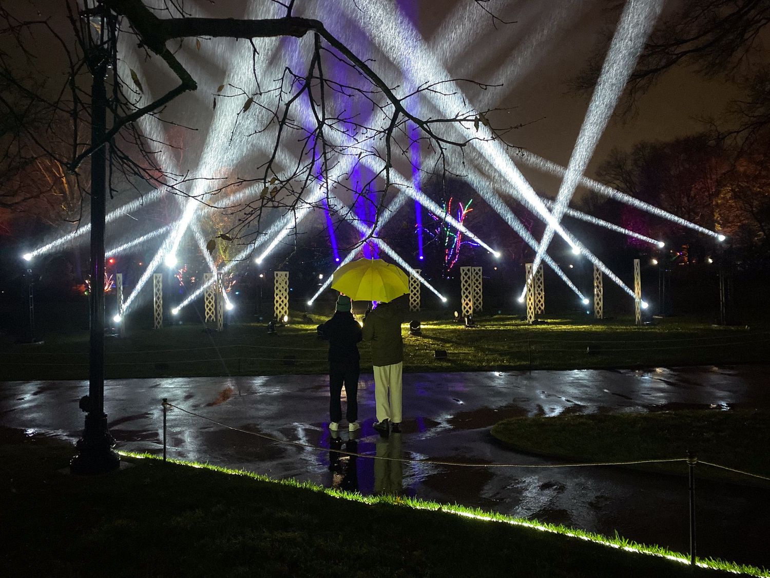 Dramatic light show with white and purple beams illuminating a figure in yellow.