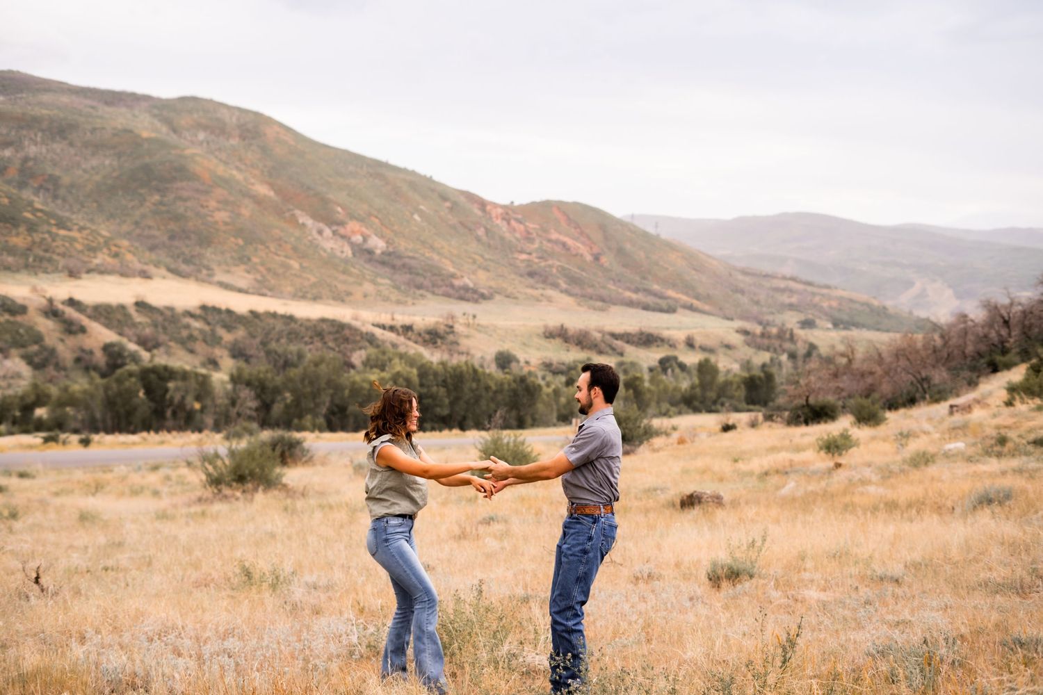 Couple dancing together in a scenic mountainous field during golden hour.