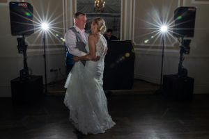 A couple dancing at their wedding reception with dramatic lighting effects.