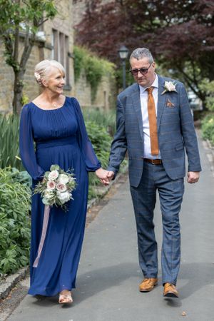 A couple in formal attire walking along a garden path. Bakewell Bath Gardens.