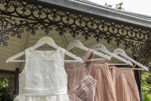 Wedding dresses in white and blush pink hanging from ornate decorative trim.