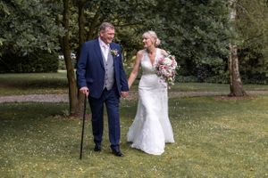 A couple walking together on their wedding day in a sunny garden.