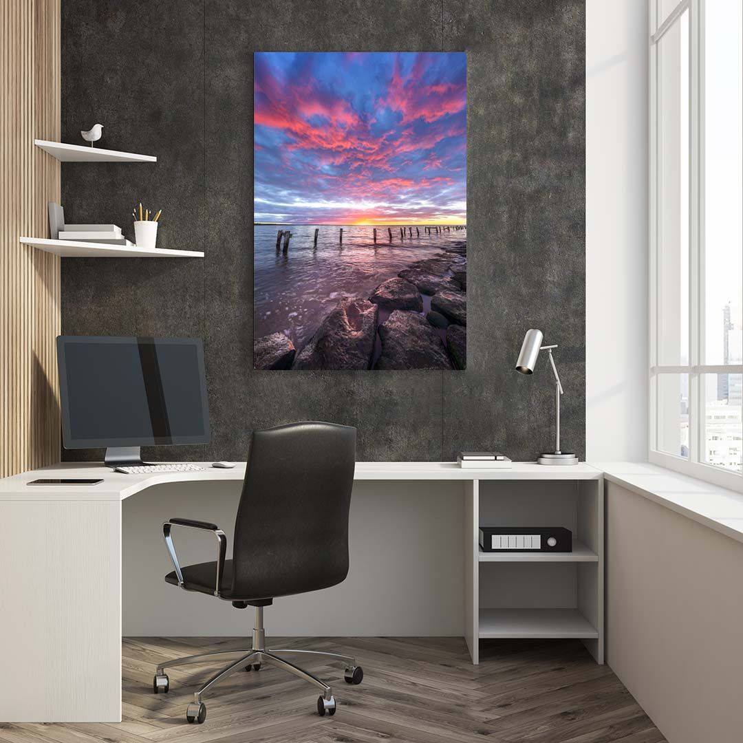 Modern home office setup with vibrant sunset seascape artwork displayed on dark wall.