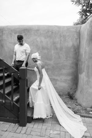 A black and white wedding portrait featuring a long trailing dress on outdoor steps.