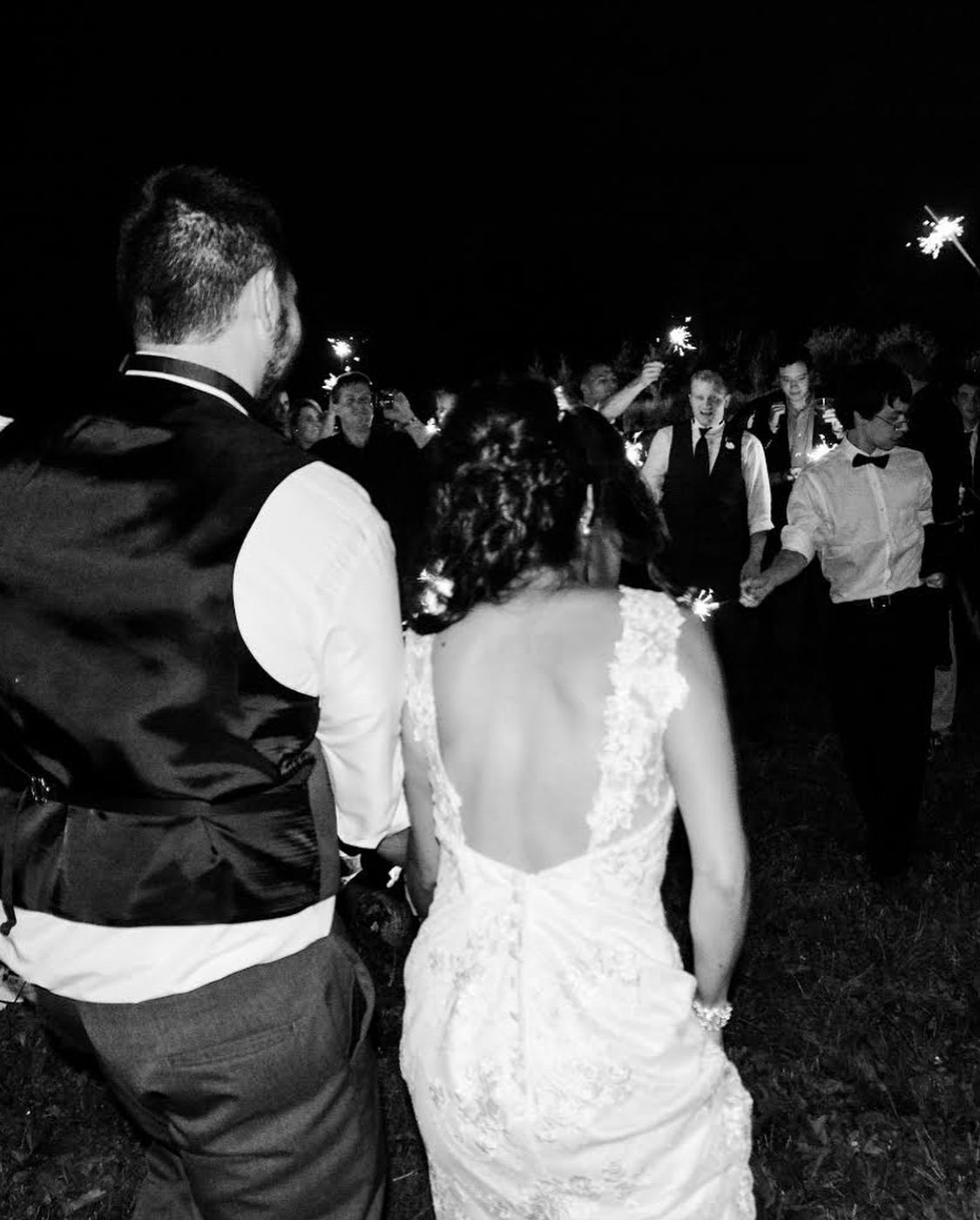 Newlyweds exiting through sparklers at their nighttime wedding celebration.