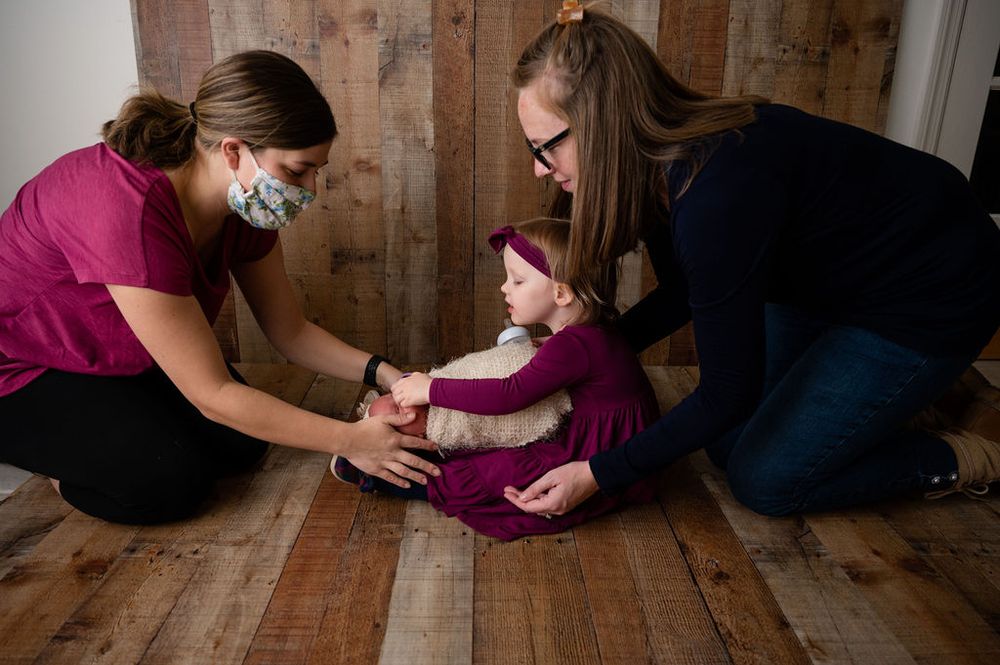 Medical professionals in protective masks examine small child on wooden floor.