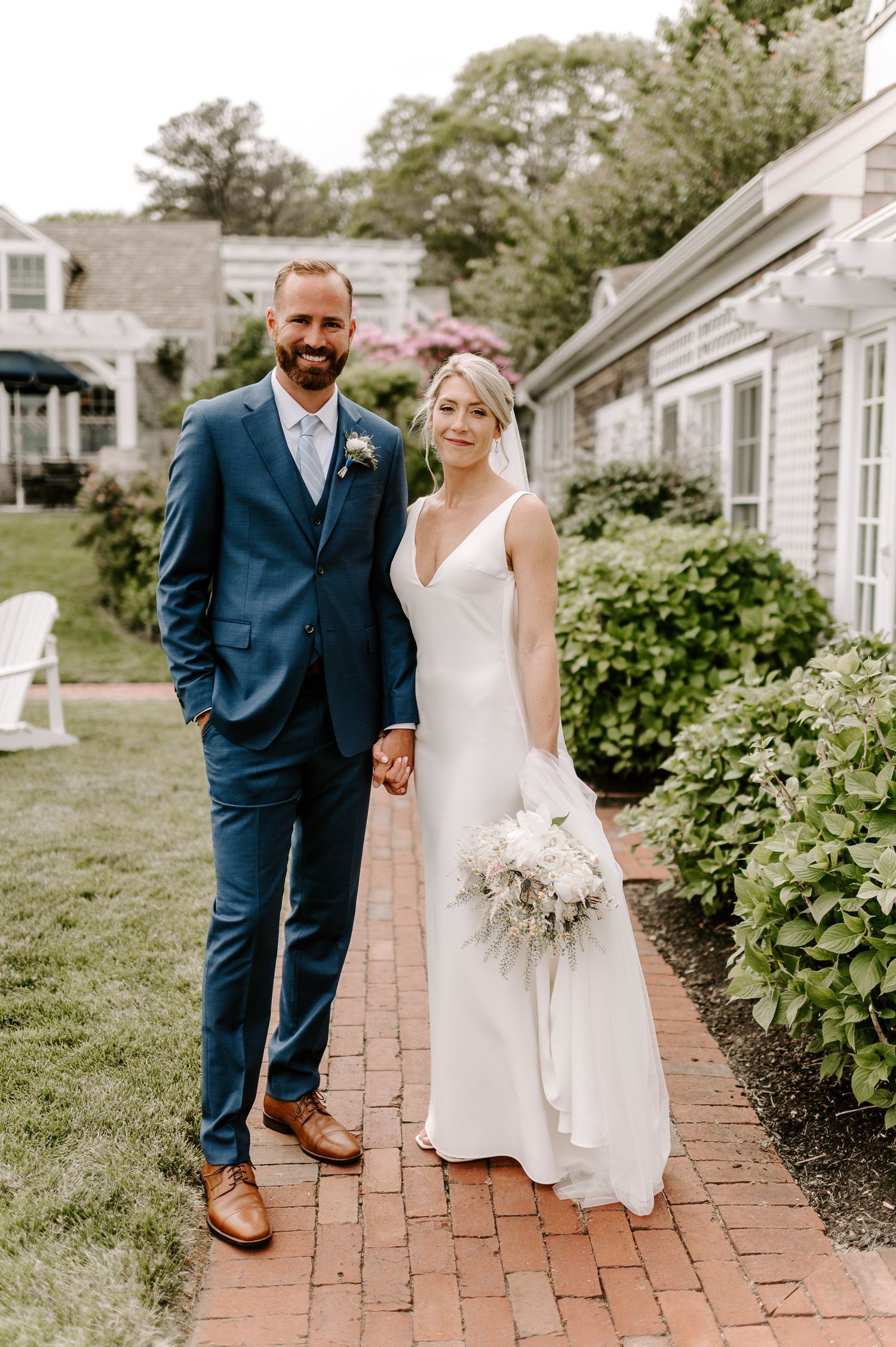 Bride and groom pose together on brick pathway with classic architecture in background.