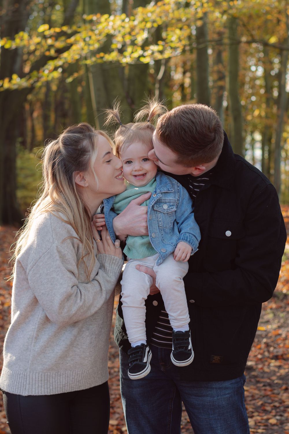 A family shares a tender moment together in a forest setting during autumn.
