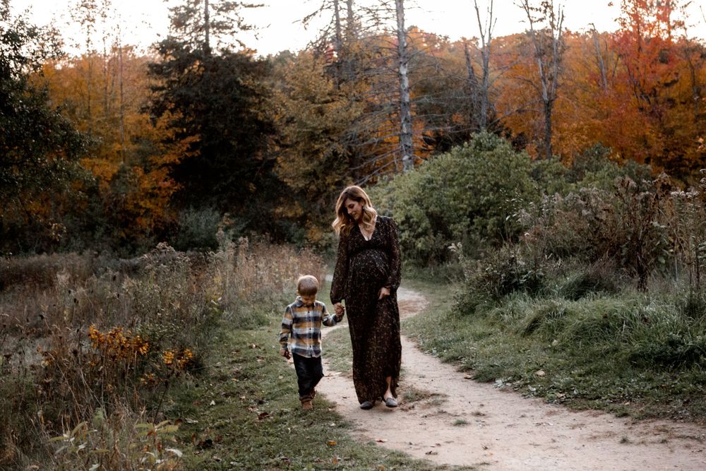 A family plays together in a scenic autumn field during golden hour sunset.