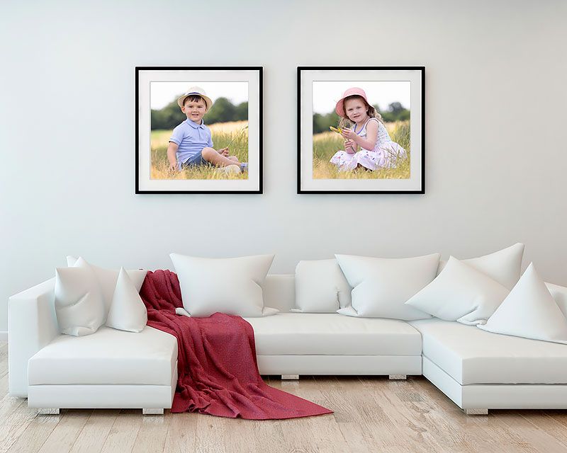 Modern living room interior with white sectional sofa and two square portrait frames.