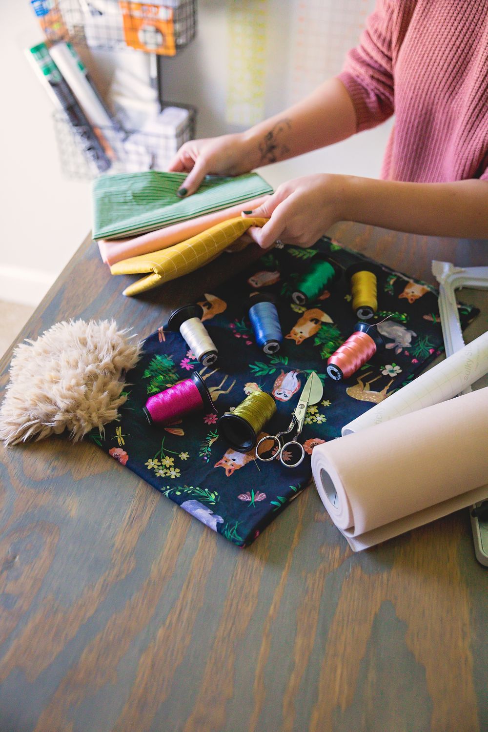 Colorful thread spools and sewing supplies arranged on a dark wooden surface.