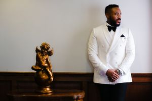 Elegant white tuxedo with decorative gold cherub statue in formal setting.
