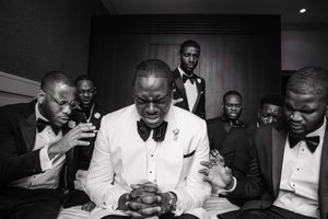 Groomsmen in formal attire gather around during wedding preparations.