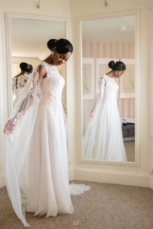 Bride in elegant white lace gown admires her reflection in mirror.