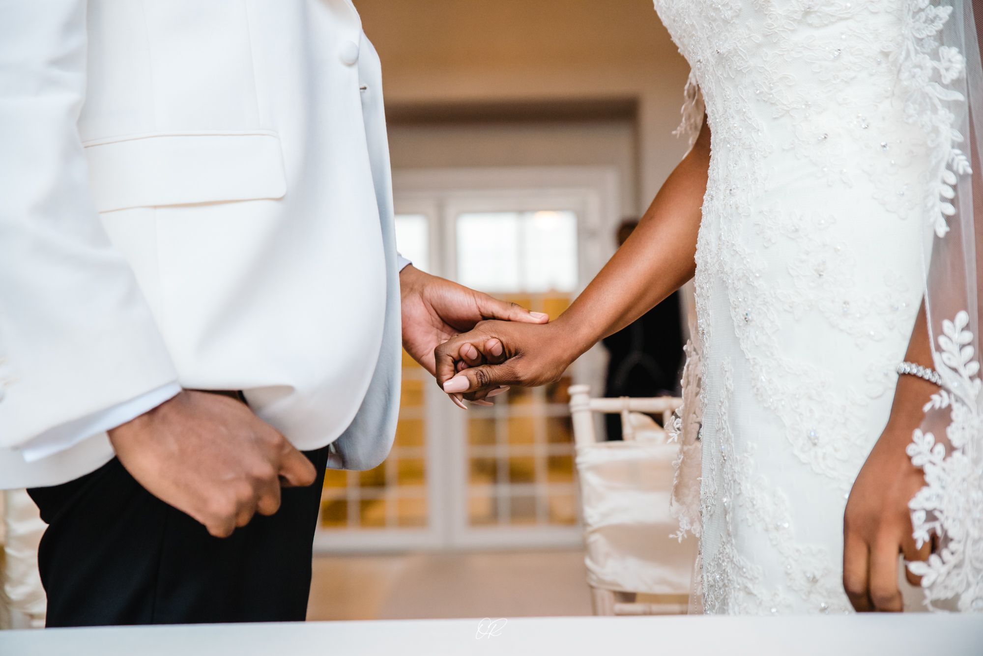 Close-up of couple holding hands during intimate wedding moment.