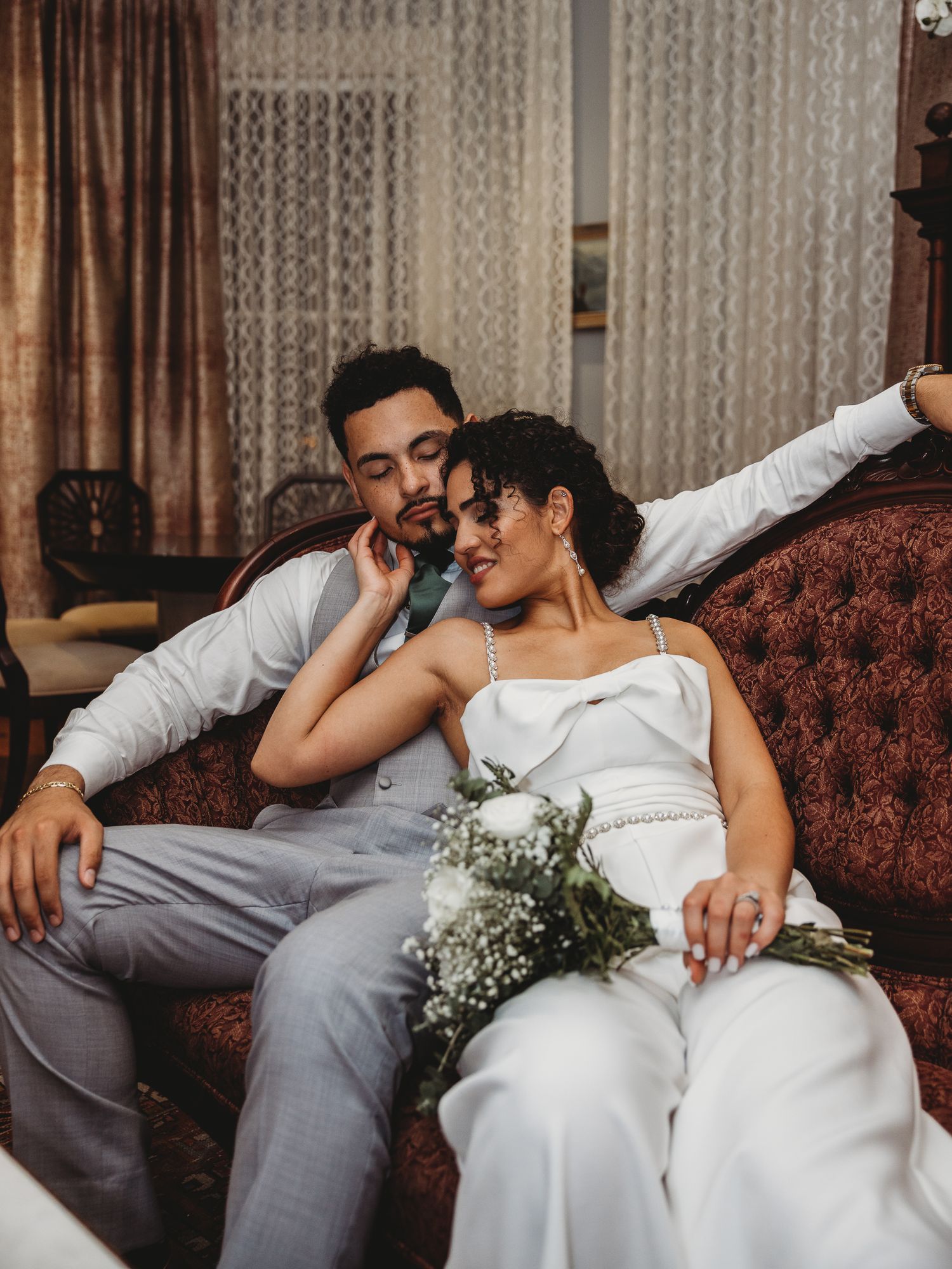 Intimate portrait of a couple just married reclined on a couch, Dr. Phillips House, Orlando Florida.