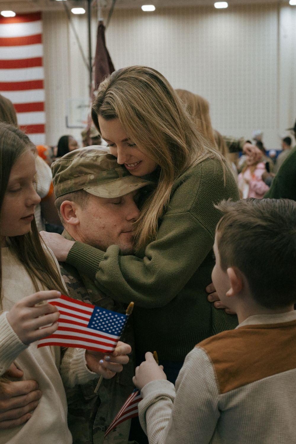 An emotional military homecoming moment with family members and an American flag.