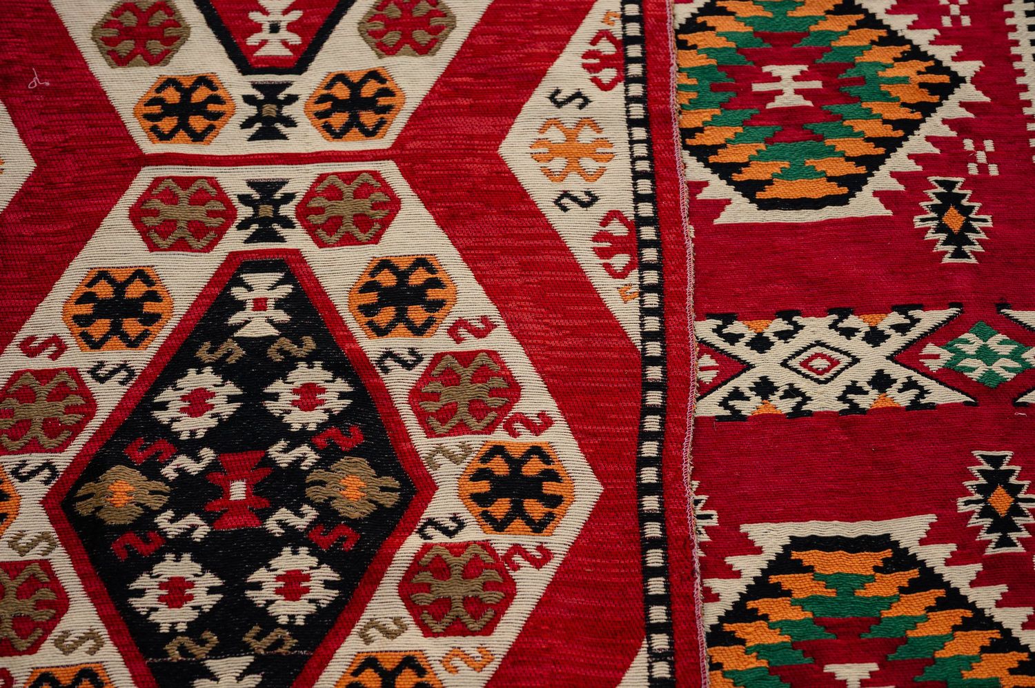 Close-up detail of a traditional red Middle Eastern carpet with geometric patterns and designs.