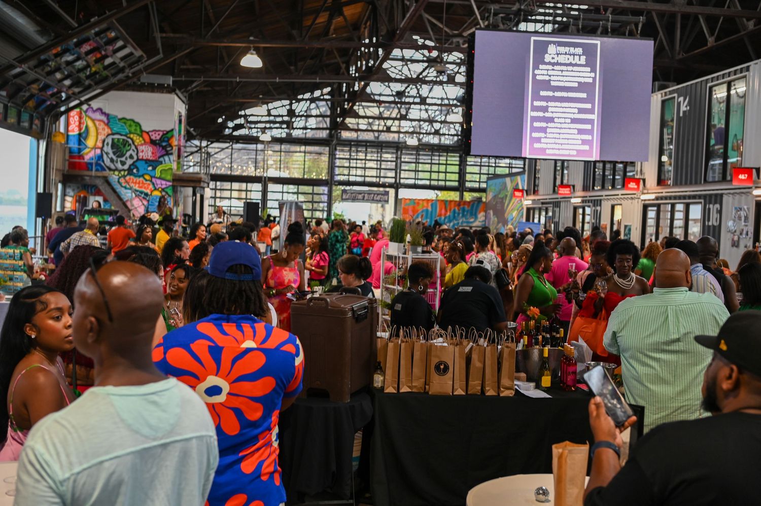 A crowded indoor market event with colorful decorations and vendor booths filled with shoppers.