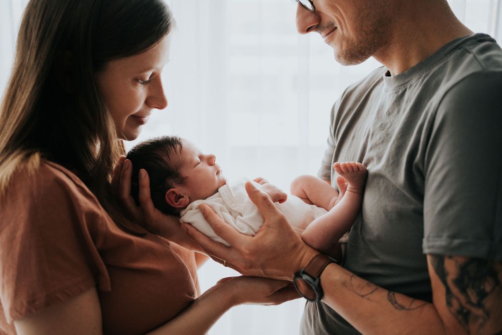 mama i tata czule obejmują noworodka - sesja noworodkowa Kraków