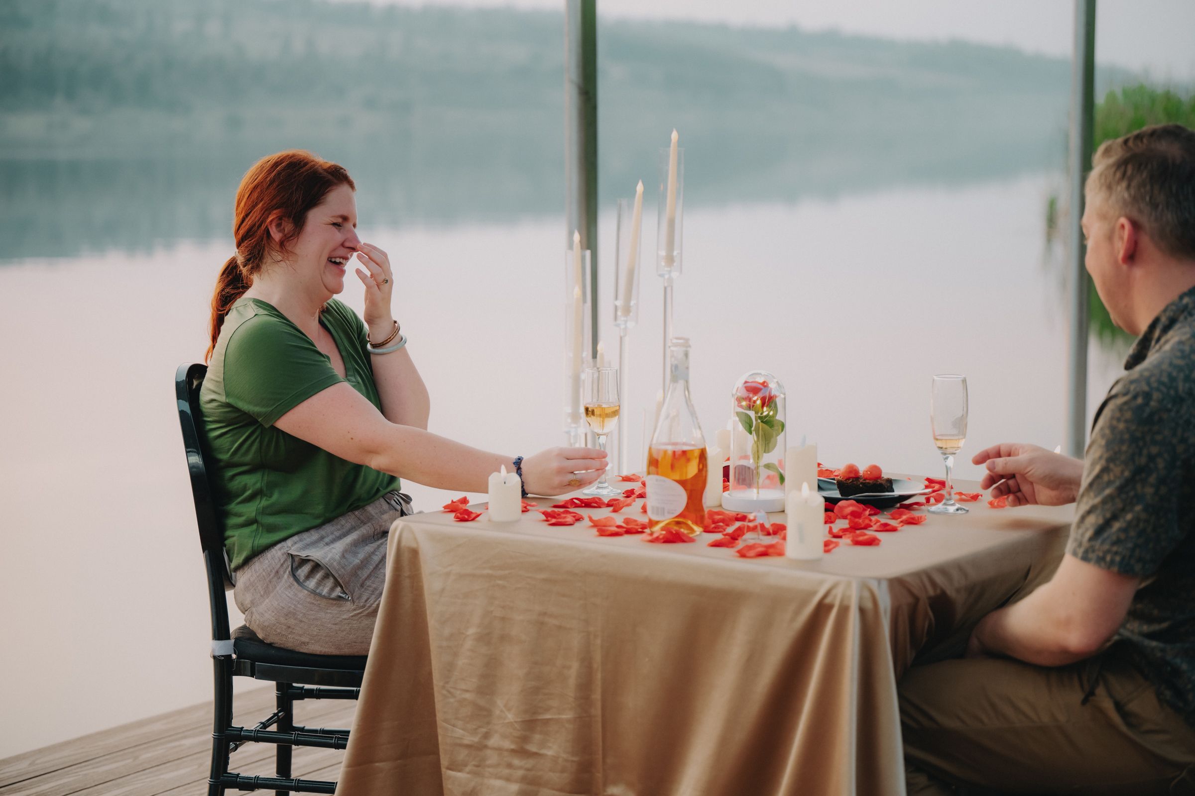 Candlelit dinner setting with multiple people seated at a long wooden table enjoying an indoor meal.