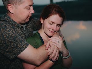 Two people sharing a tender embrace at sunset, with warm soft lighting and intimate atmosphere.