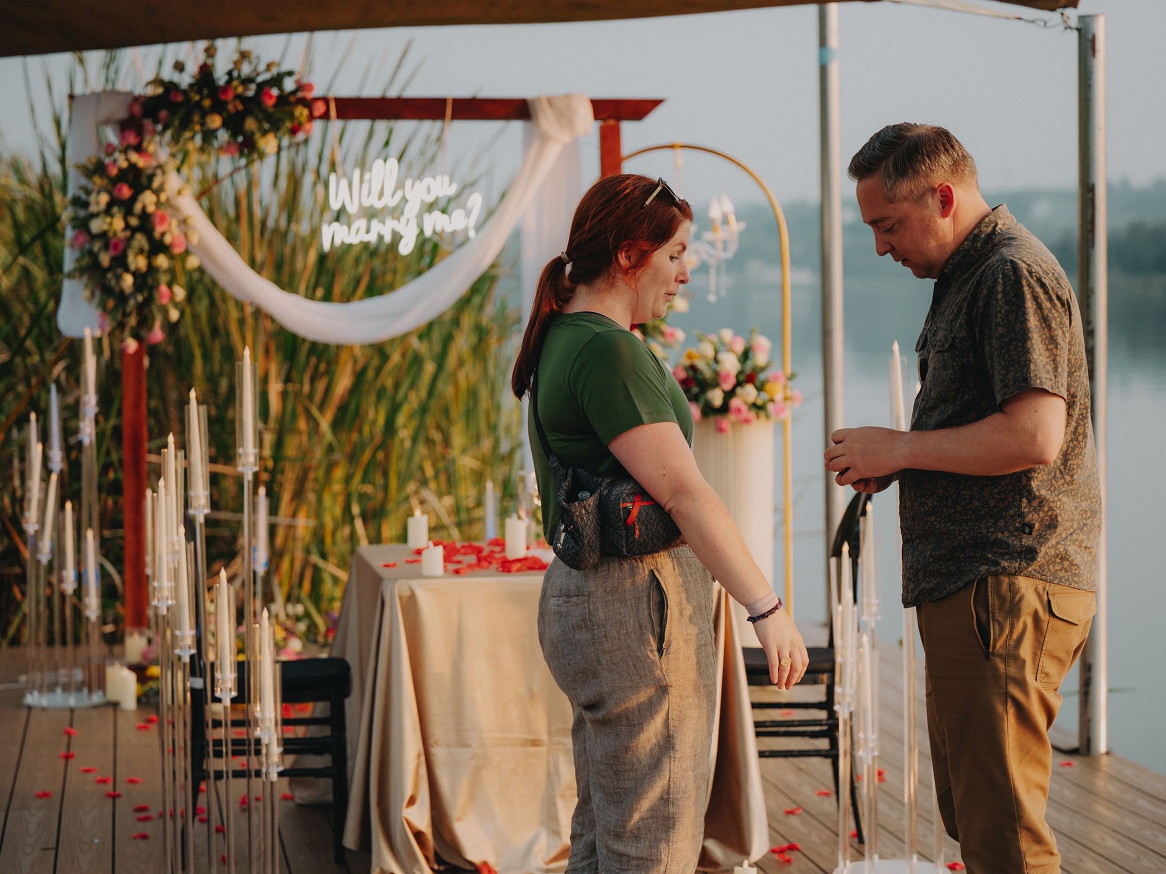 A romantic beach wedding ceremony with flower decorations and a white arch against the ocean backdrop during sunset.