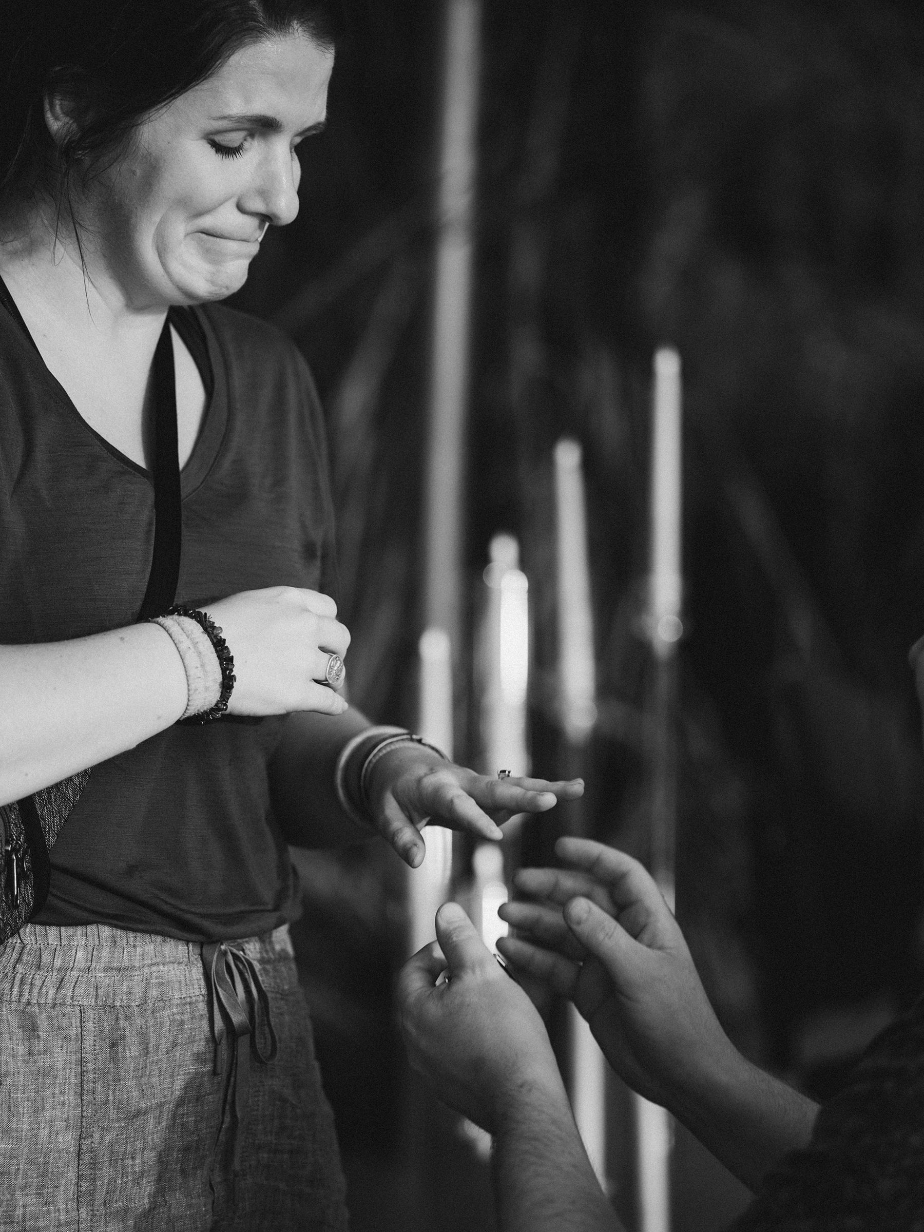 Close-up sequence of hands gently placing a ring, shown in moody black and white lighting.