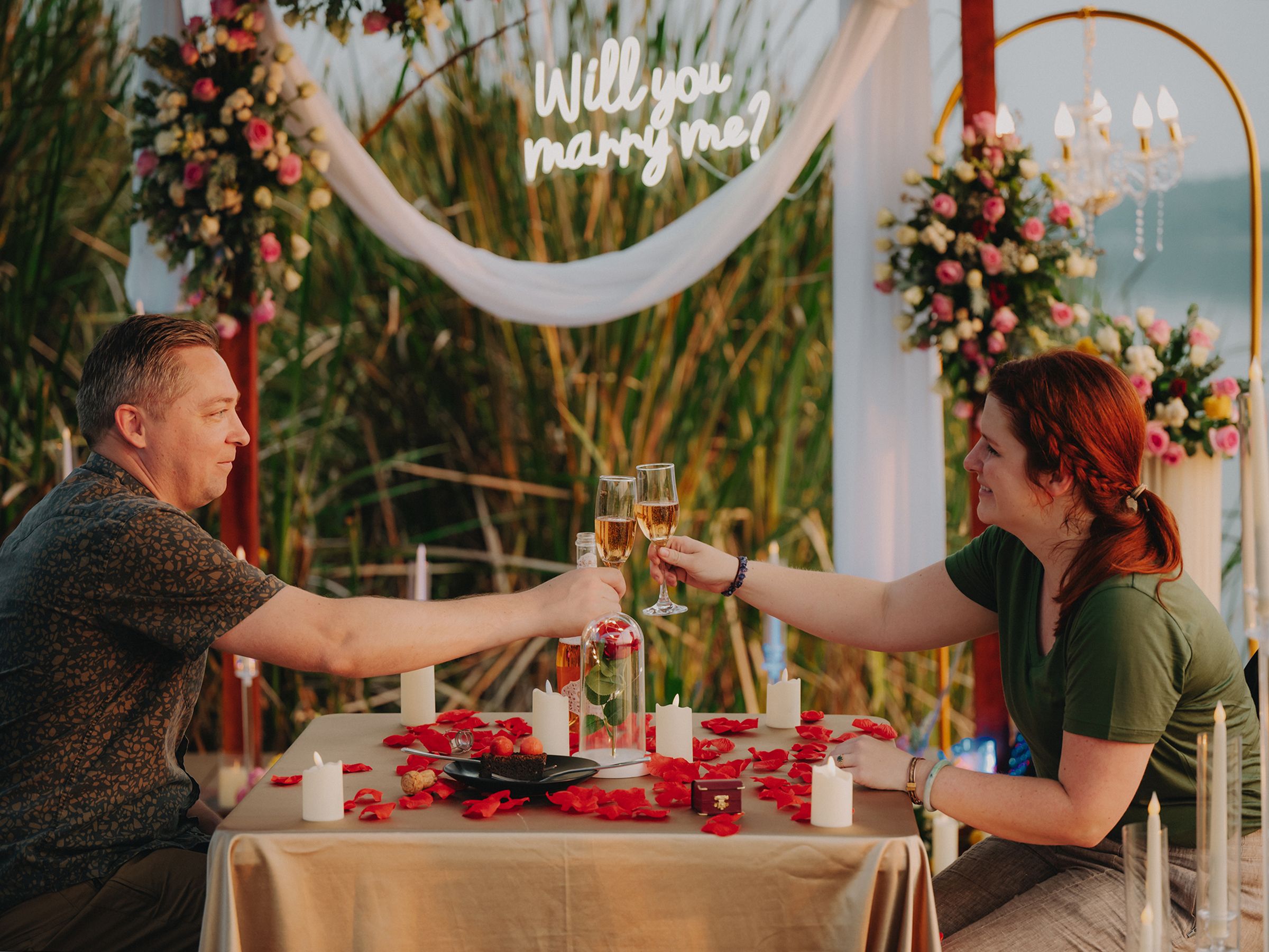A collection of wedding reception dining tables decorated with red and white floral arrangements and candlelight.