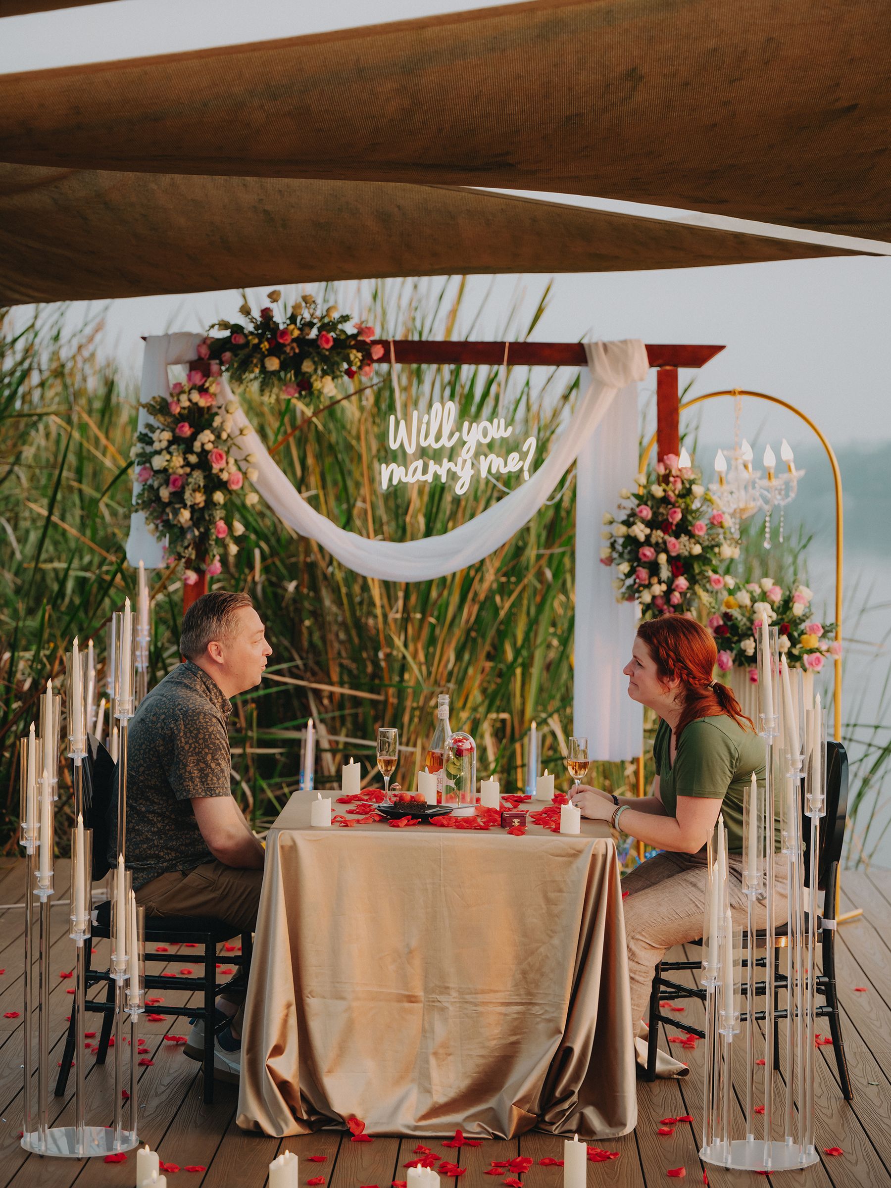Elegant wedding reception table setup with flowing fabric, tall candlesticks and floral arrangements in rustic venue.