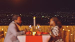 Romantic dinner table setting at night with city lights twinkling in the background.