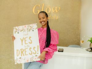 A person in pink holding a 'YES DRESS' sign at Glow Bridals.