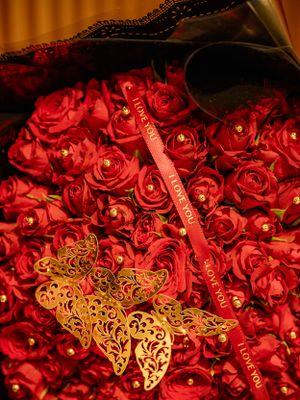 Red roses and golden butterfly decorations arranged in an elegant bouquet.