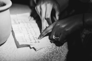 Close-up of hands writing on paper with a pen in black and white.