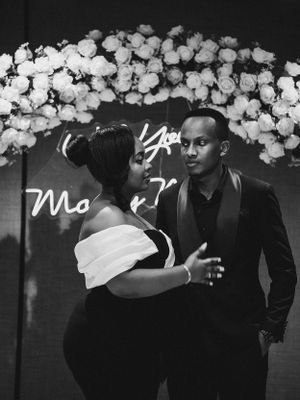 Romantic proposal setup with white floral arch and neon sign.