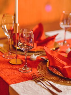 Elegant table setting with wine glasses and orange linens for a formal dinner.