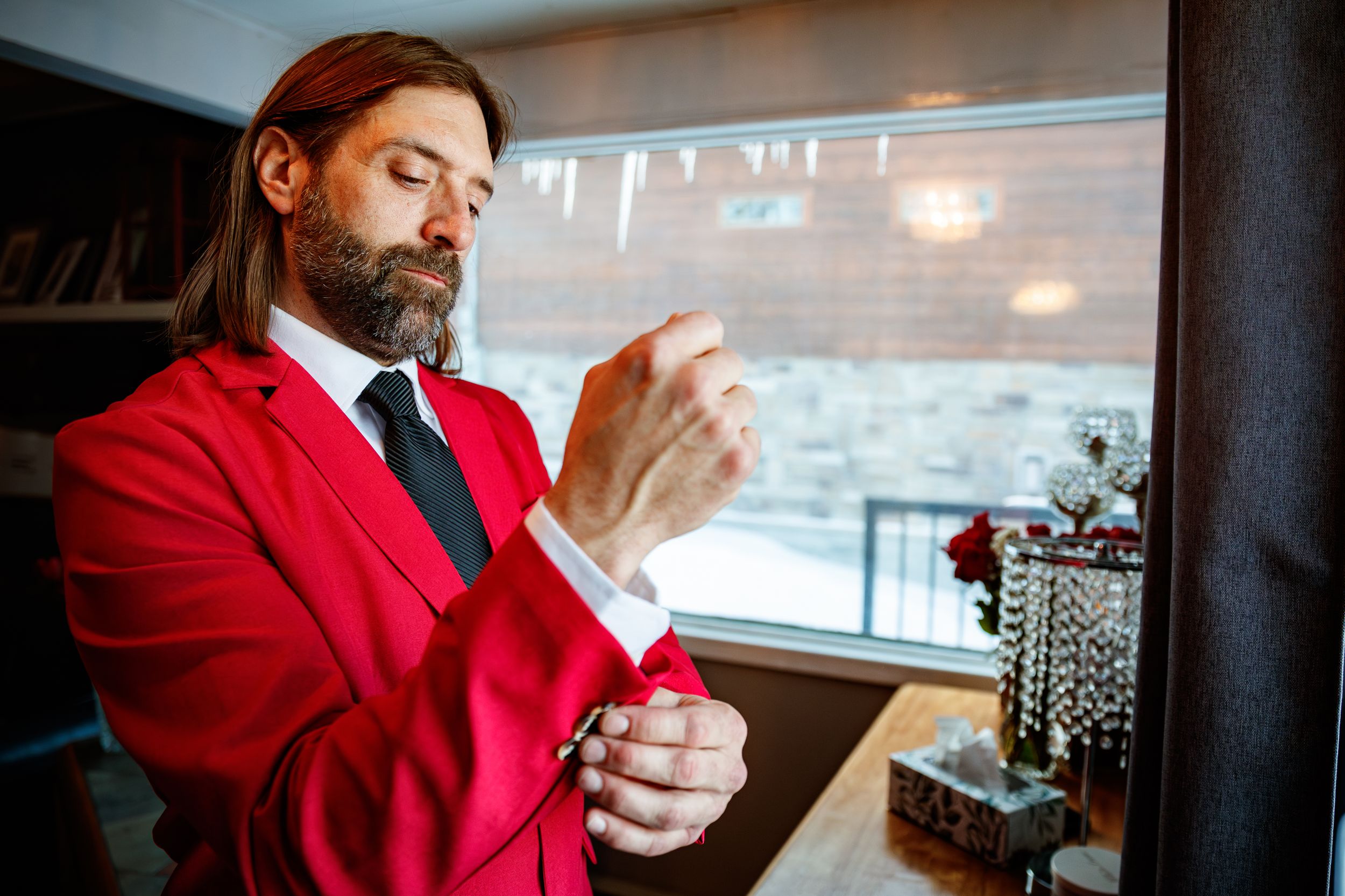 Professional in a bright red suit examines phone screen while sitting in modern office setting.