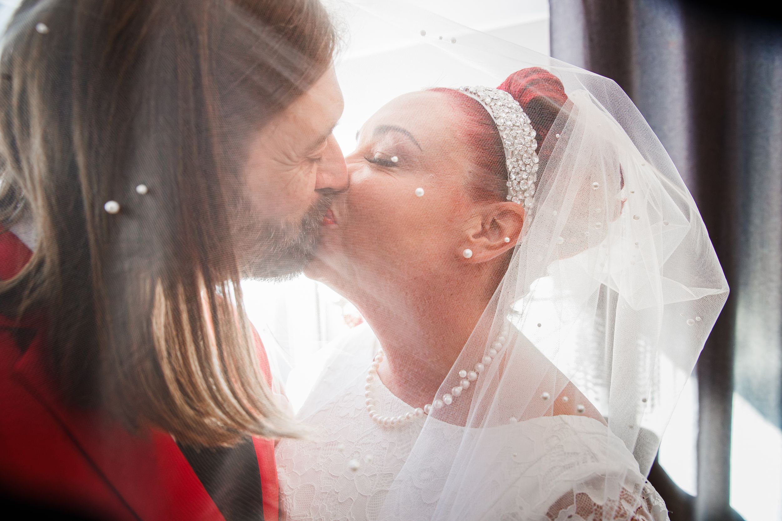 Couple sharing a tender moment in their wedding attire against a light-filled background.