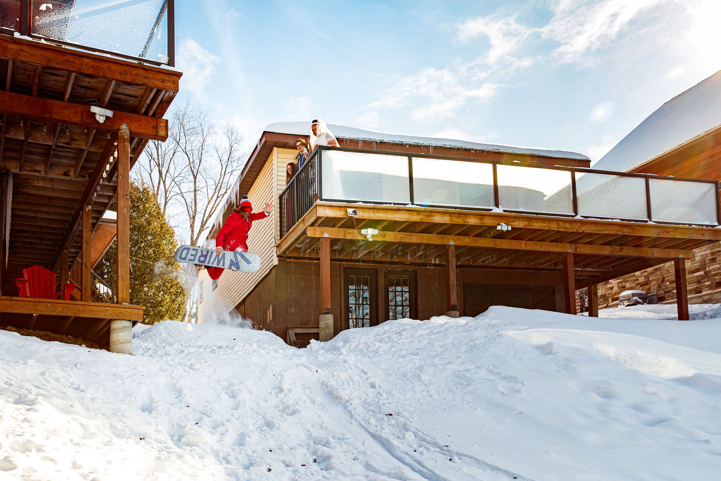 Sequence of snowboarding action shots showing a jump progression over a snow-covered terrain with buildings in background.