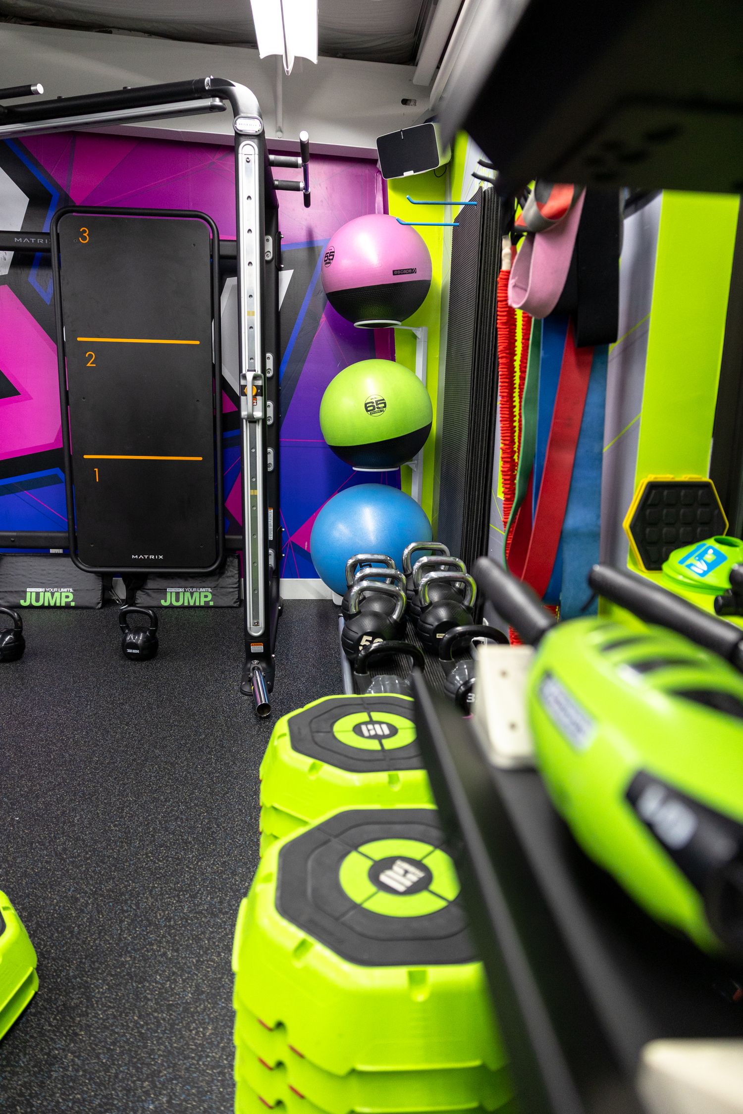 Colorful mobile gym interior with medicine balls, resistance bands, green weight plates, and numbered workout equipment.